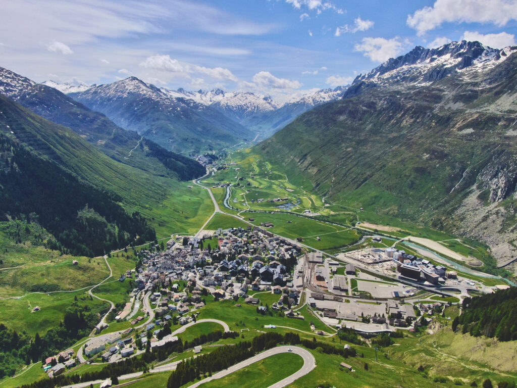Aerial view of Andermatt valley surrounded by the Swiss Alps, representing Interalps’ connection to nature and authentic Swiss living.